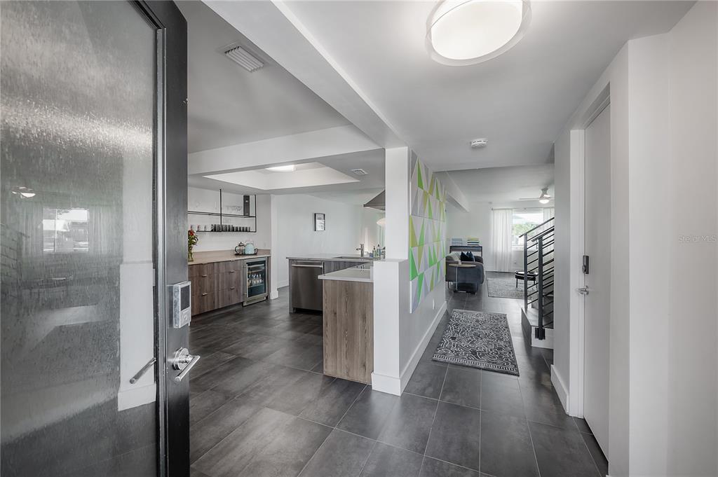 An entryway leads into a modern kitchen with dark tile floors and wood cabinetry — 8757 BAY POINTE DRIVE, TAMPA, FL