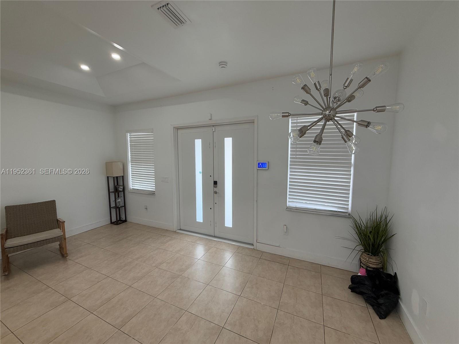 A bright entryway features tile flooring, a modern sputnik chandelier, and double front doors — 12202 SW 216th St, Miami FL 33170, MIAMI, FL