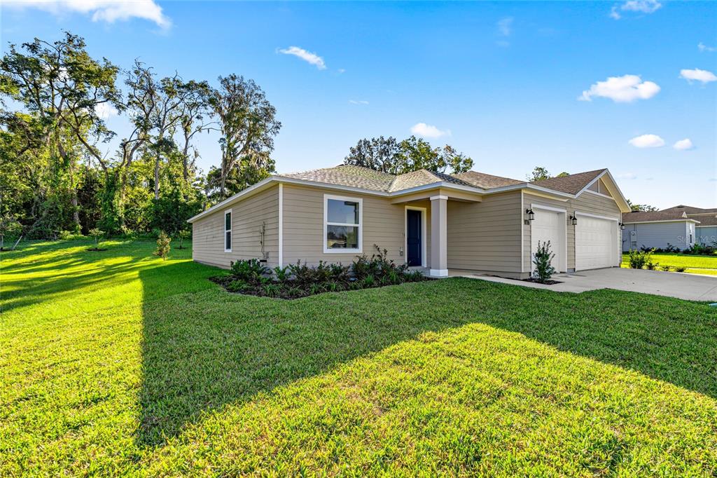 A single-story house with tan siding, a two-car garage, and a green lawn — 8059 SW 45TH COURT, OCALA, FL