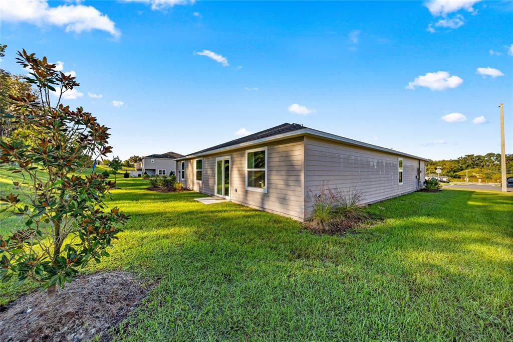 The exterior of a single-story house with light-colored siding and a grassy backyard — 8059 SW 45TH COURT, OCALA, FL