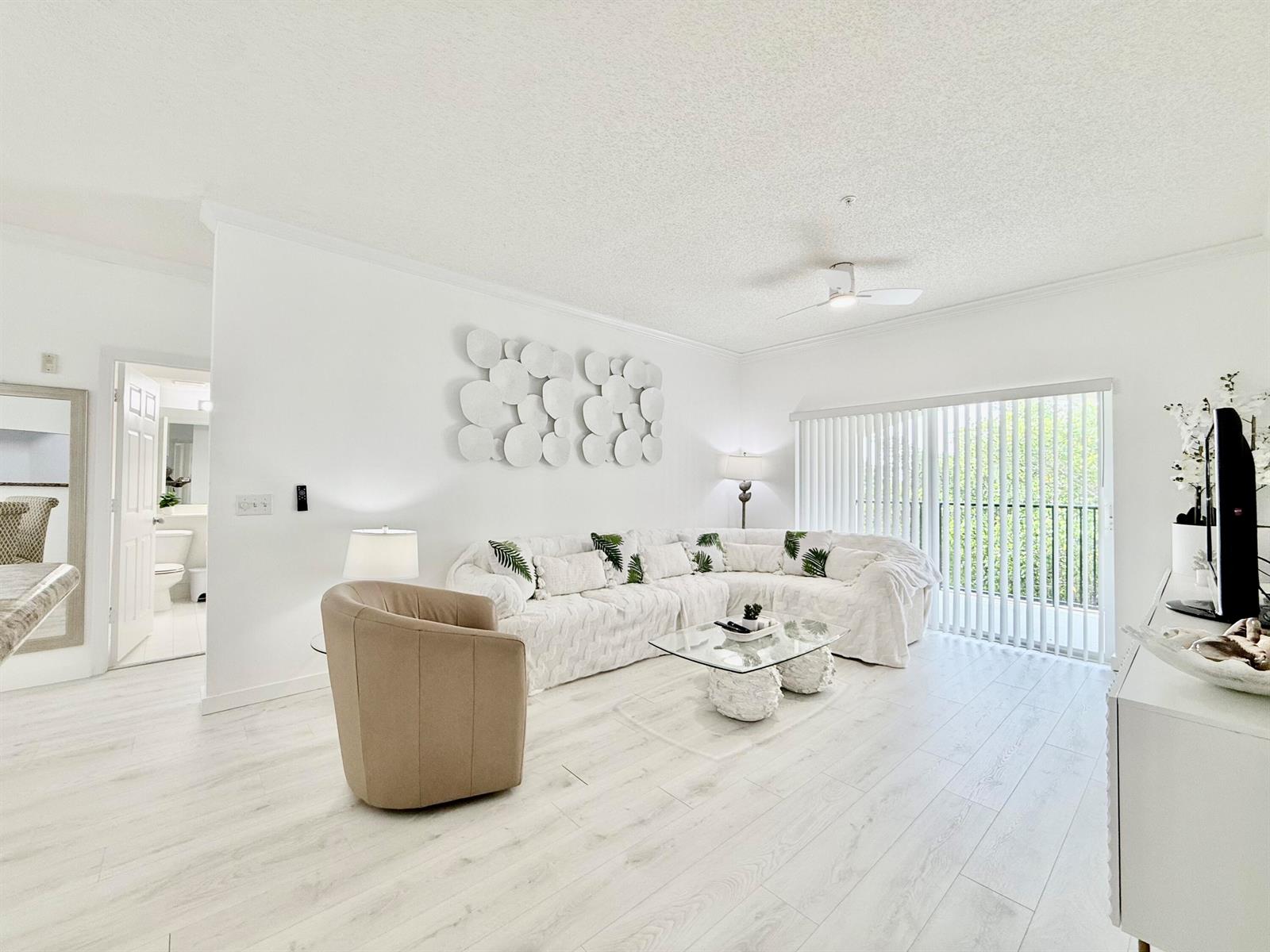 A bright living room features a white sectional sofa, a glass coffee table, and light flooring — 4404 Tuscany Way # 4404, Boynton Beach FL 33435, BOYNTON BEACH, FL