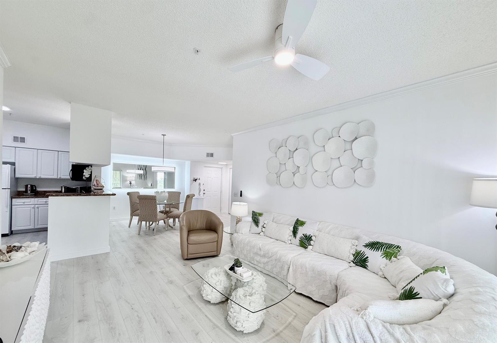 A bright living room features a white sectional sofa, glass coffee table, and dining area — 4404 Tuscany Way # 4404, Boynton Beach FL 33435, BOYNTON BEACH, FL