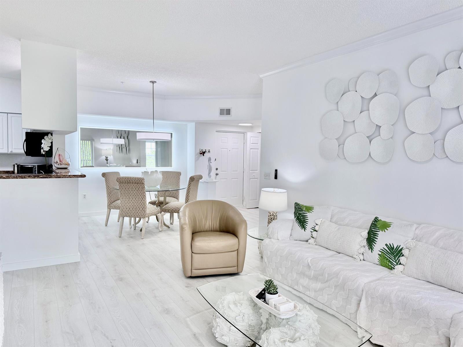 A bright living and dining area features white walls, light wood flooring, and modern furniture — 4404 Tuscany Way # 4404, Boynton Beach FL 33435, BOYNTON BEACH, FL