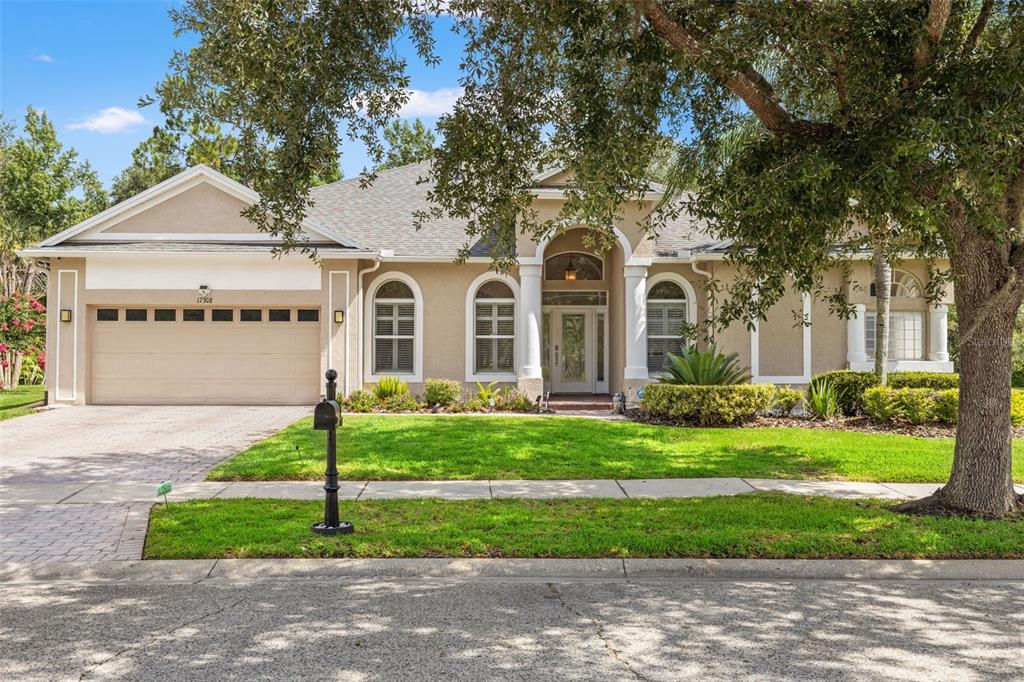 A single-story suburban house with a tan stucco exterior, arched windows, and a two-car garage — 17308 CHENANGO LANE, TAMPA, FL