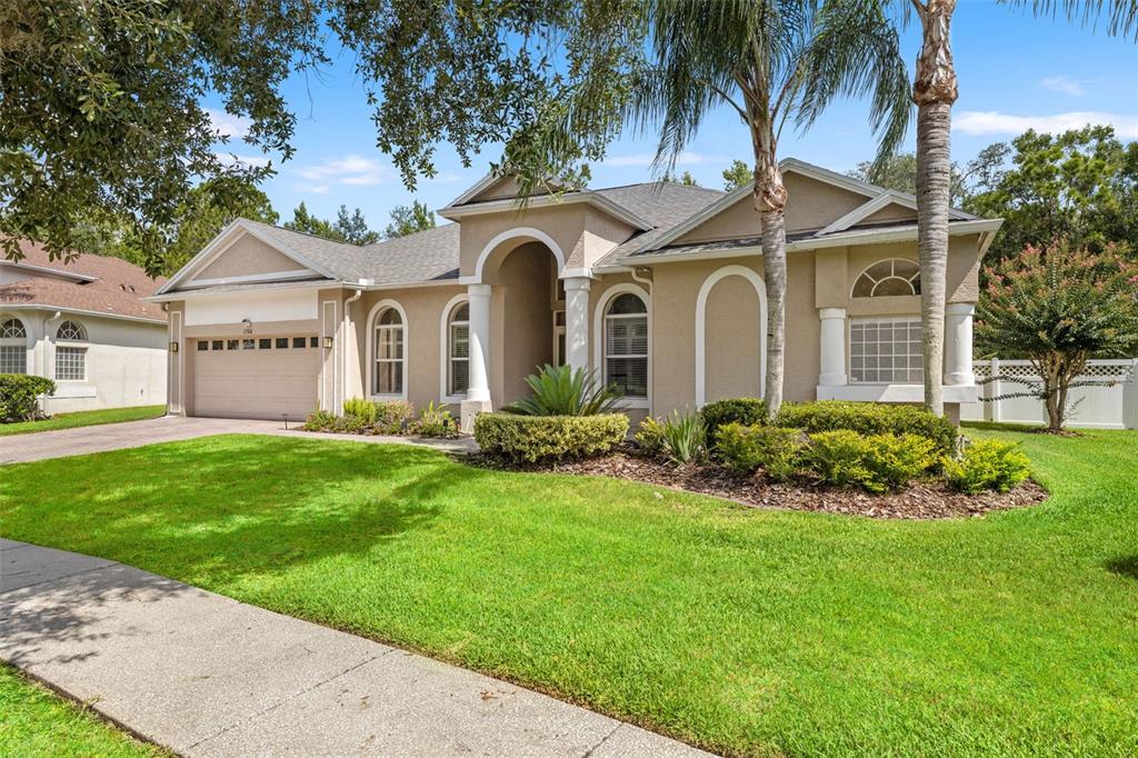 A tan single-story suburban house with a two-car garage and a front arched entryway — 17308 CHENANGO LANE, TAMPA, FL