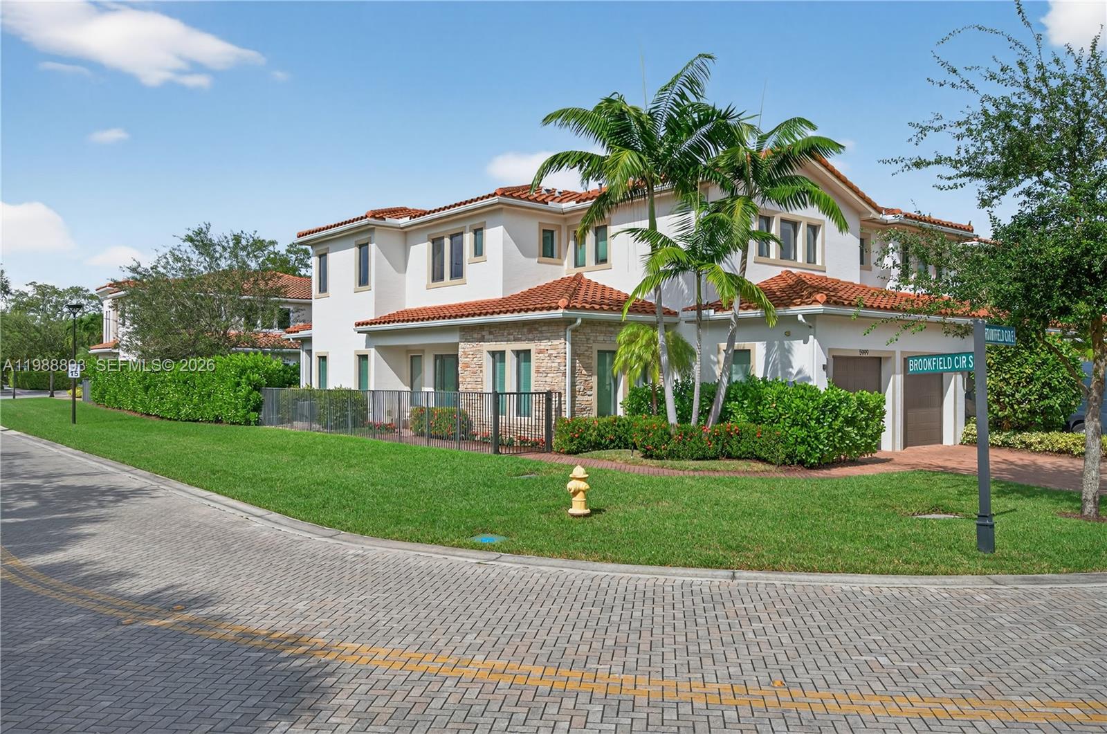 A two-story stucco house with a tile roof and palm trees sits on a corner — 5999 E Brookfield Cir E, Hollywood FL 33312, HOLLYWOOD, FL
