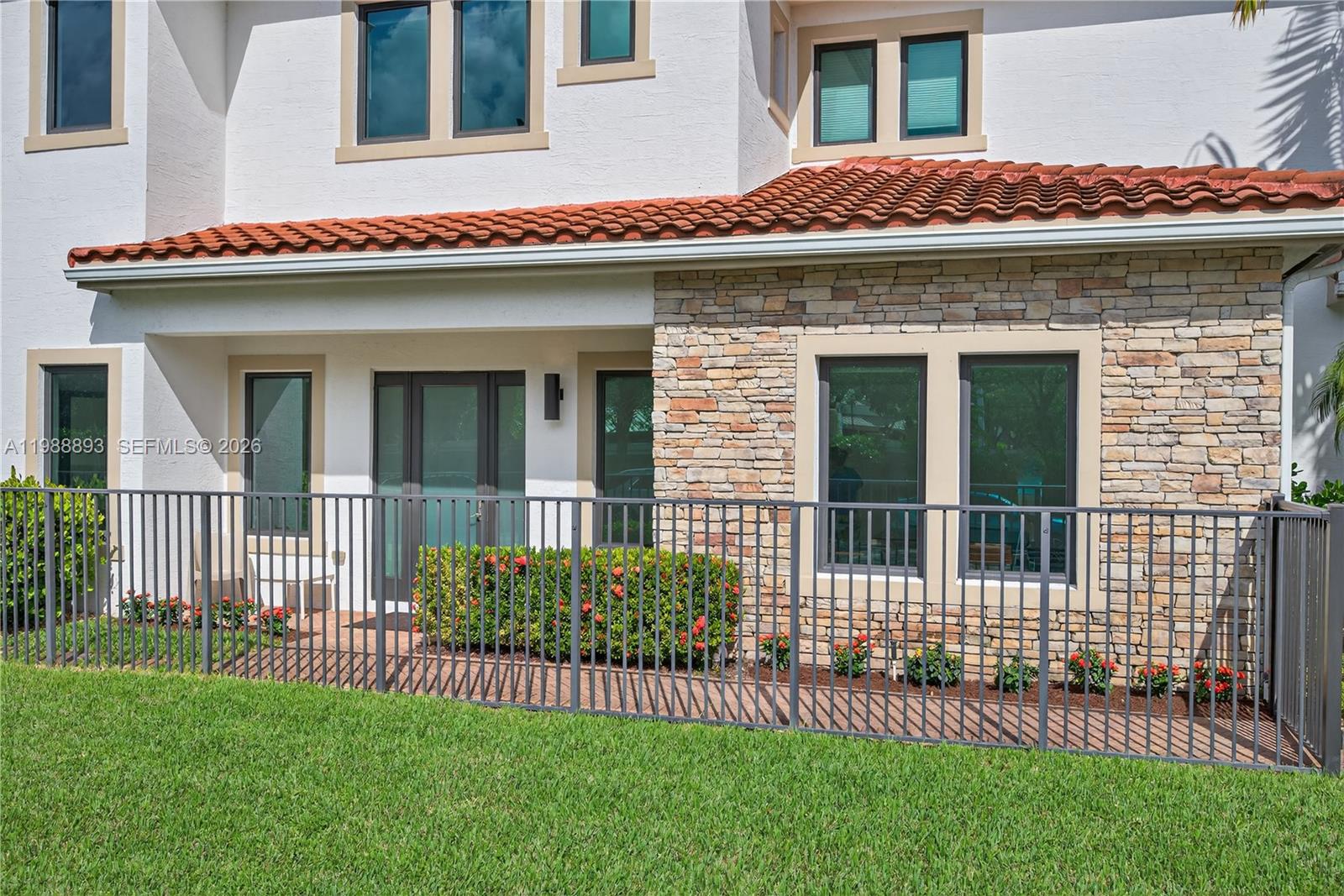 A patio with a metal fence sits in front of a house with stone siding — 5999 E Brookfield Cir E, Hollywood FL 33312, HOLLYWOOD, FL