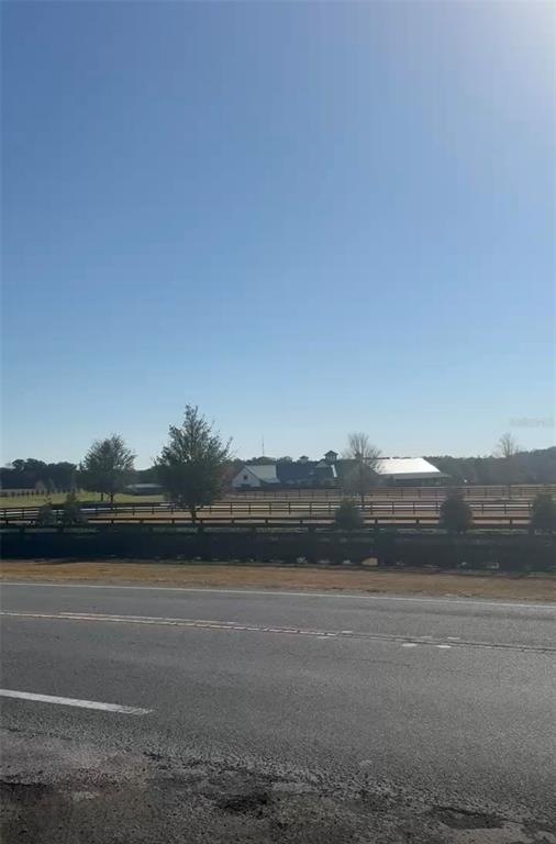 A view from a road looking across a fenced pasture toward a large barn structure — SW 148TH CT 32 ND PLACE, OCALA, FL