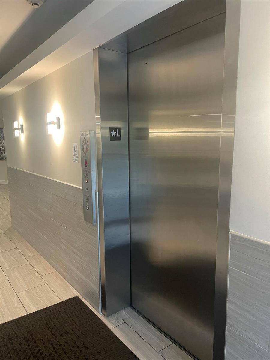 A stainless steel elevator door is set into a wall with gray tile wainscoting — 955 Egret Circle # 411, Delray Beach FL 33444, DELRAY BEACH, FL