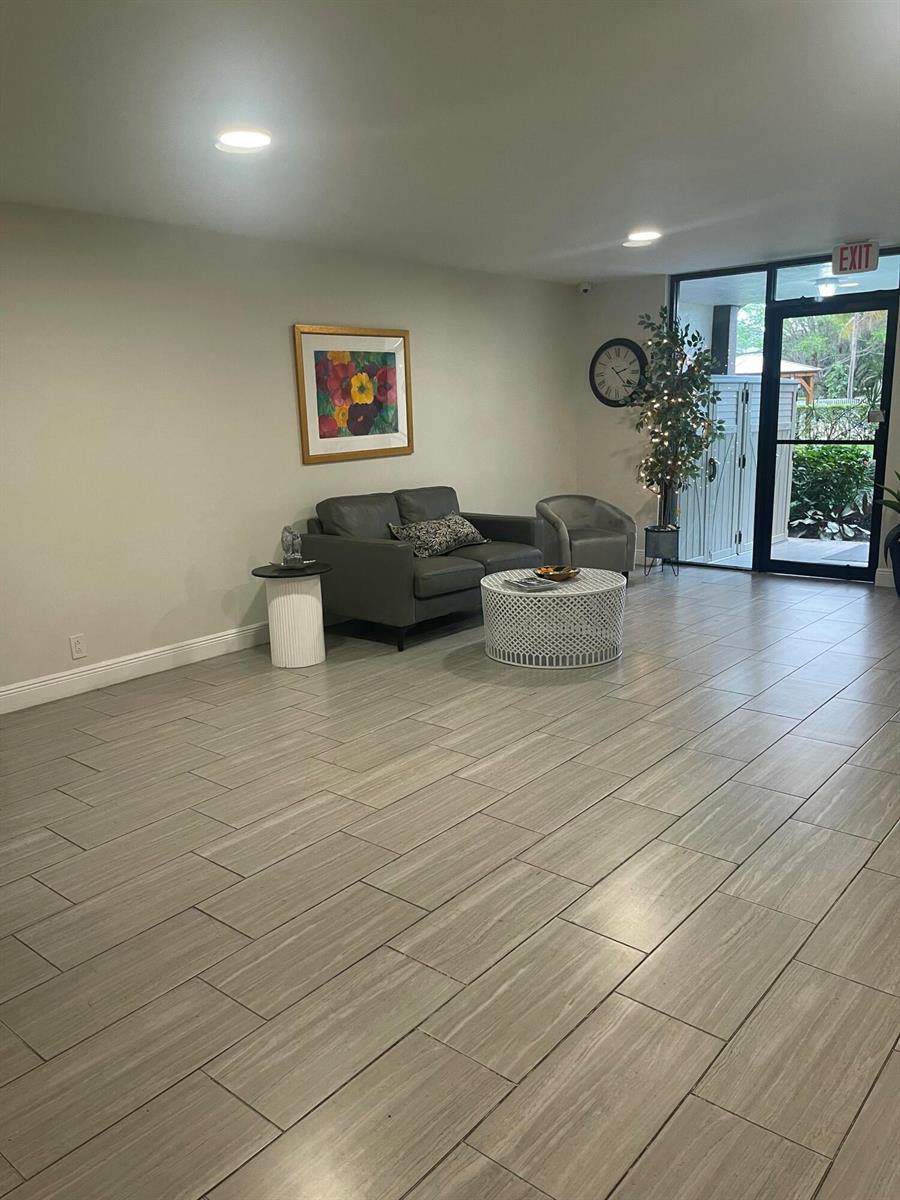 A waiting area features gray tile flooring, a gray loveseat, and a white coffee table — 955 Egret Circle # 411, Delray Beach FL 33444, DELRAY BEACH, FL