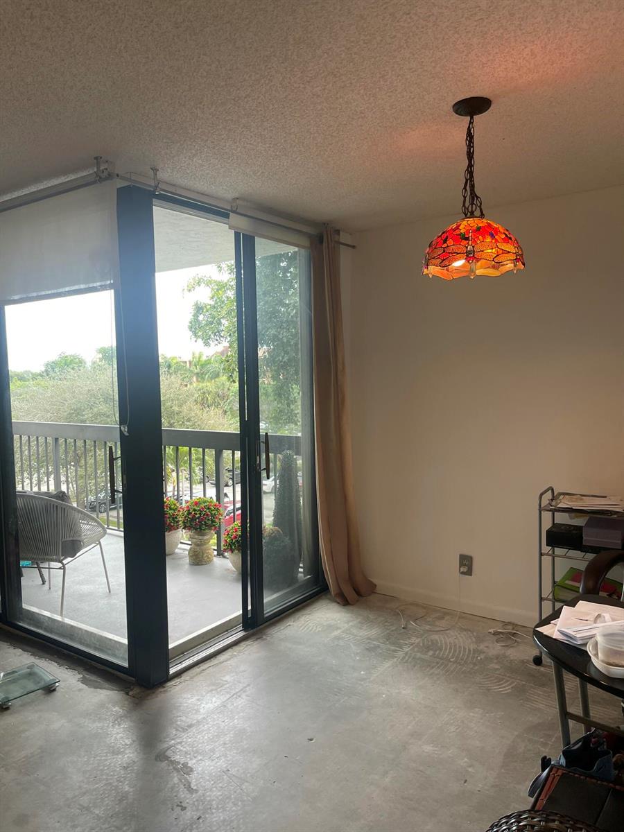 A room with concrete flooring, a stained glass pendant light, and a sliding glass door — 955 Egret Circle # 411, Delray Beach FL 33444, DELRAY BEACH, FL