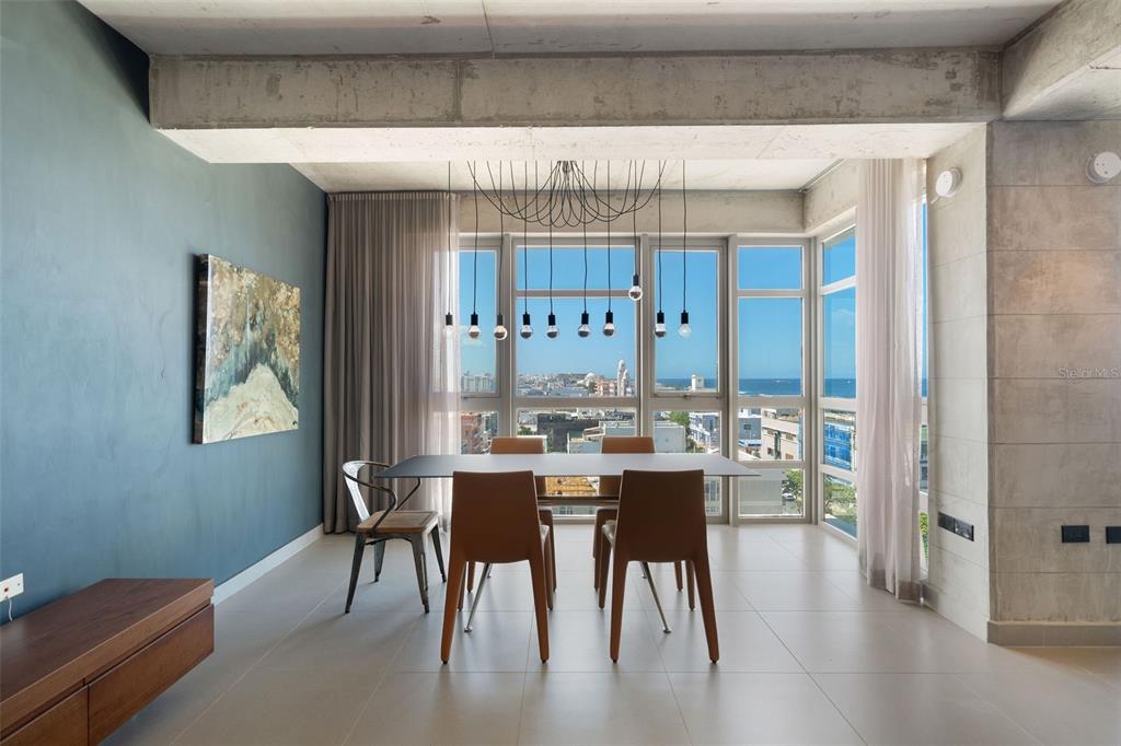 A dining area features a modern table, tan chairs, a unique pendant light, and ocean views — 404 DE LA CONSTITUCION AVENUE UNIT 708, SAN JUAN, PR