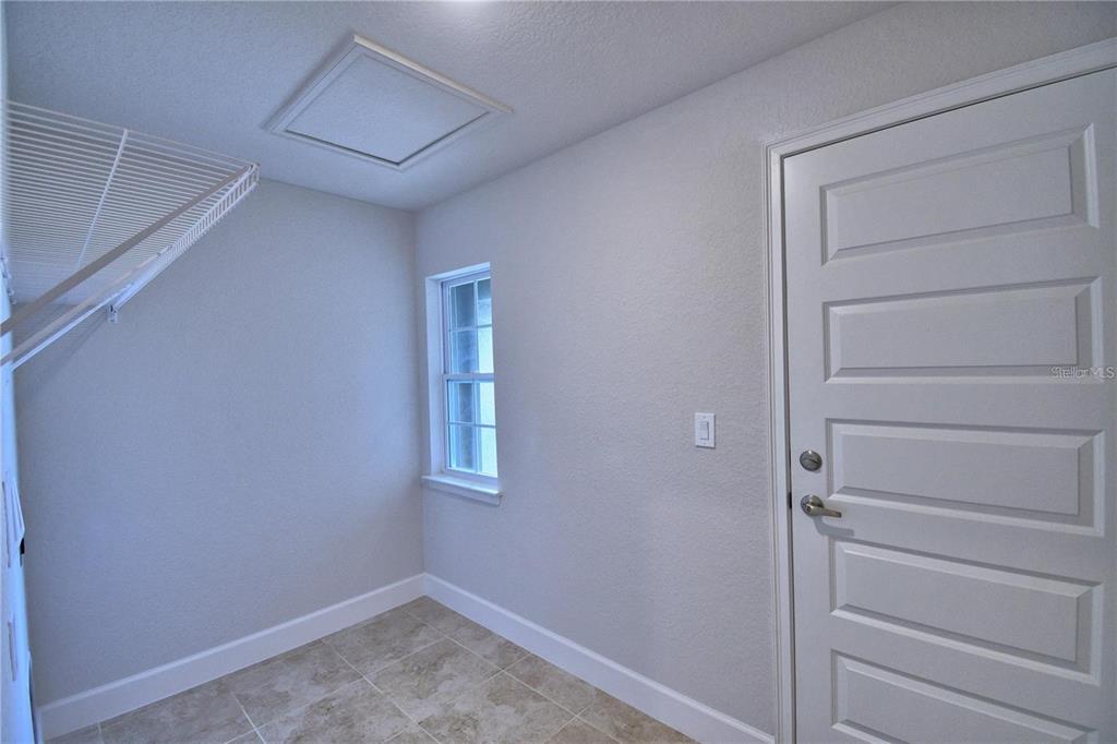 A laundry room features a white door, a window, and a wire storage shelf — 1734 CARNOSTIE ROAD, WINTER HAVEN, FL