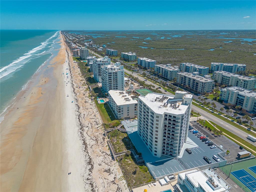 An aerial view of a coastal beach with multiple high-rise condominium buildings and parking lots — 5207 S ATLANTIC AVENUE UNIT 1123, NEW SMYRNA BEACH, FL