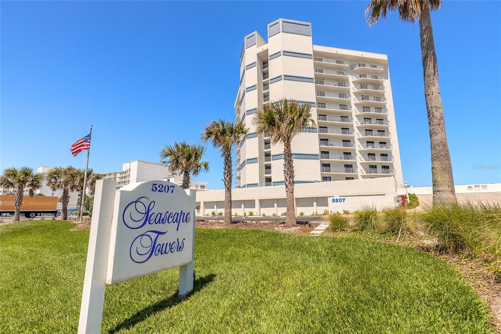 A multi-story residential building stands behind a sign for Seascape Towers on a sunny day — 5207 S ATLANTIC AVENUE UNIT 1123, NEW SMYRNA BEACH, FL