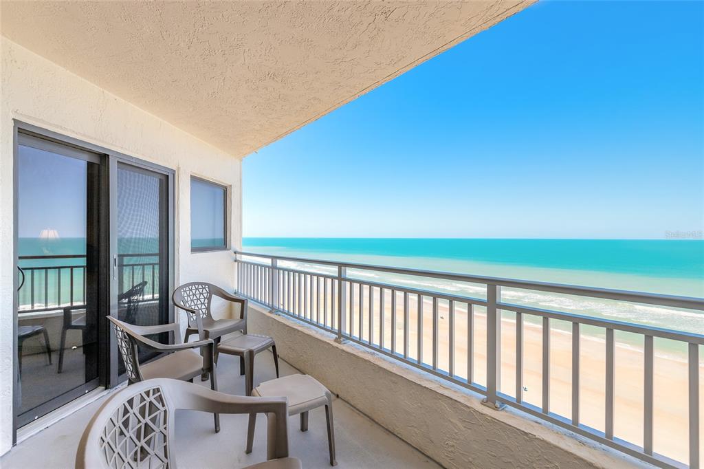 A balcony with patio furniture overlooks a sandy beach and the ocean — 5207 S ATLANTIC AVENUE UNIT 1123, NEW SMYRNA BEACH, FL