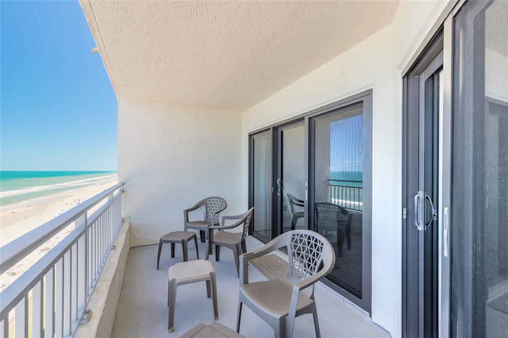 A balcony with plastic chairs overlooks a sandy beach and the ocean — 5207 S ATLANTIC AVENUE UNIT 1123, NEW SMYRNA BEACH, FL