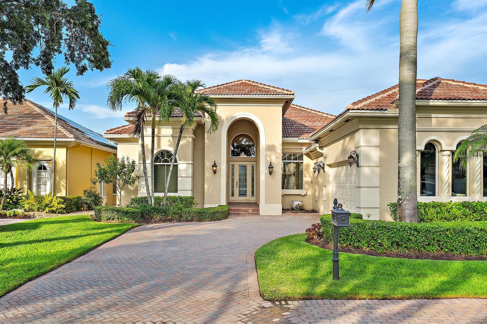 A beige stucco house with a tiled roof, arched entryway, and a brick paver driveway — 7440 Monte Verde Lane, West Palm Beach FL 33412, WEST PALM BEACH, FL