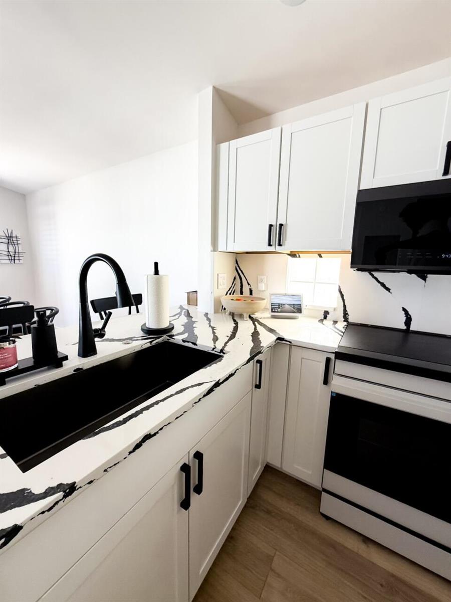 A kitchen features white cabinets, black hardware, and white countertops with bold black veining — 7895 Manor Forest Boulevard, Boynton Beach FL 33436, BOYNTON BEACH, FL