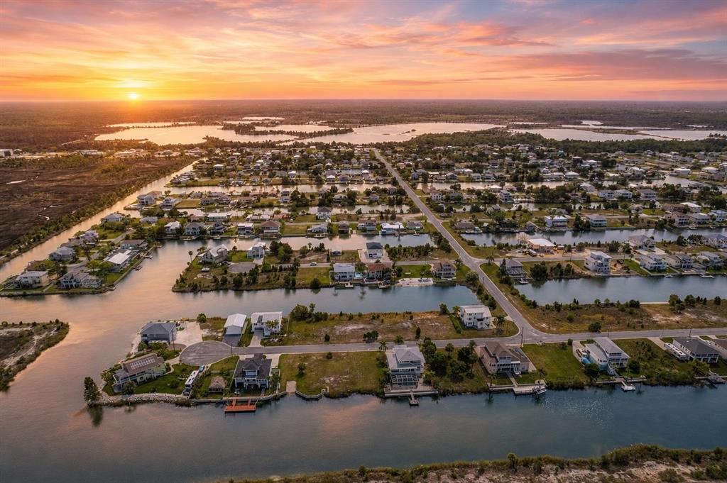 An aerial view shows waterfront houses along canals in a residential neighborhood at sunset — 3302 TURKS CAP DRIVE, HERNANDO BEACH, FL