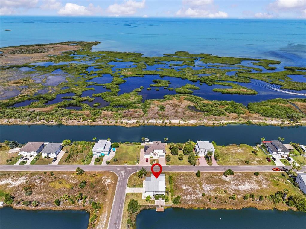 An aerial view shows a waterfront house with a red marker on a coastal lot — 3302 TURKS CAP DRIVE, HERNANDO BEACH, FL