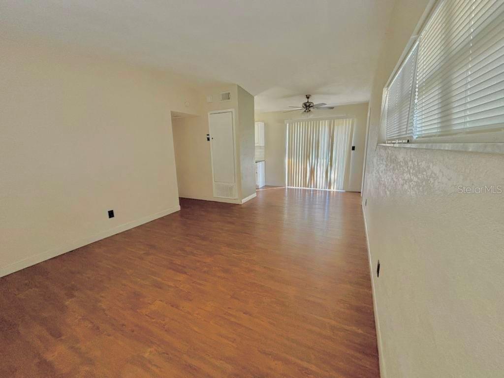 An empty room with wood-look flooring, beige walls, and a sliding glass door — 4314 SILVER STAR ROAD, ORLANDO, FL