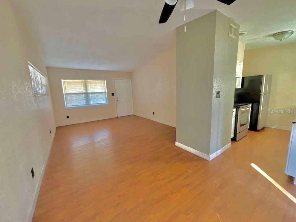 An open-concept living area with light wood-look flooring and a partial wall dividing the kitchen — 4314 SILVER STAR ROAD, ORLANDO, FL