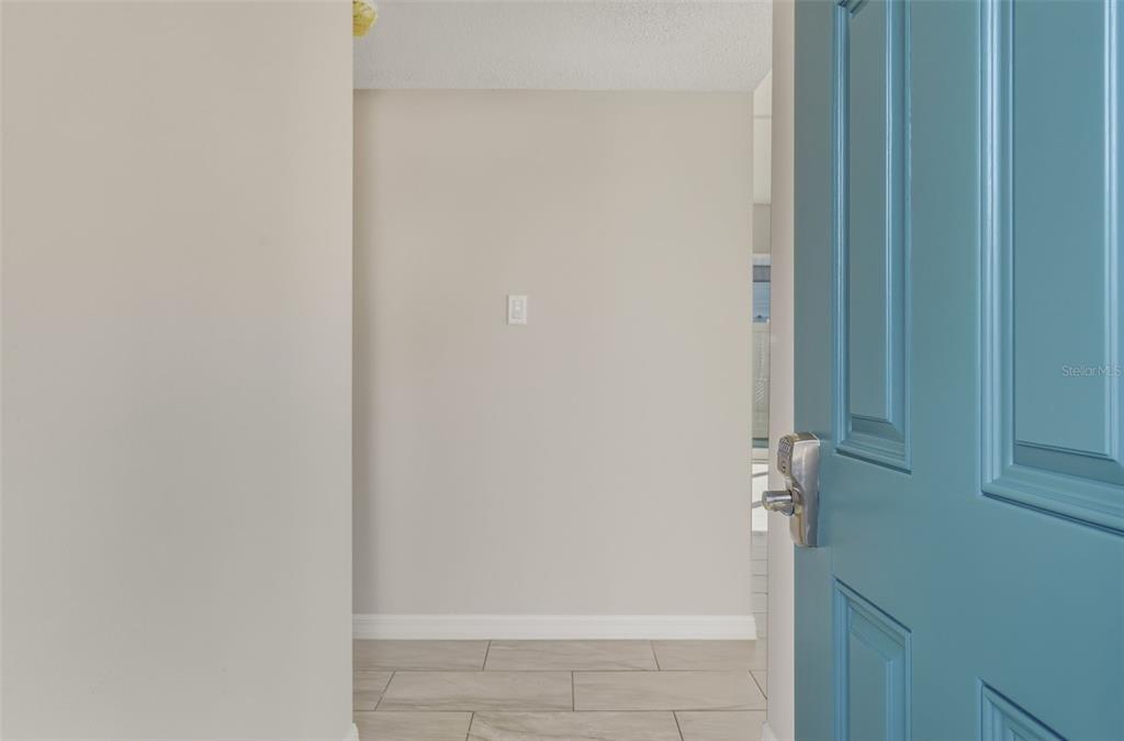 A view through an open blue door into a hallway with light-colored tile flooring — 5055 N BEACH ROAD UNIT 108, ENGLEWOOD, FL