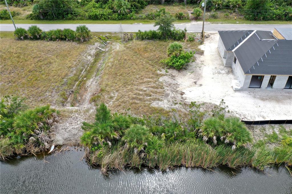 An aerial view shows a vacant lot next to a house under construction near water — 10868 MCALESTER CIRCLE, PORT CHARLOTTE, FL