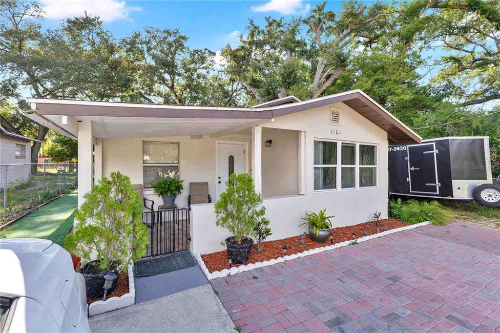 A single-story house with a covered front porch, brick paver driveway, and mature trees — 1101 28TH STREET NW, WINTER HAVEN, FL