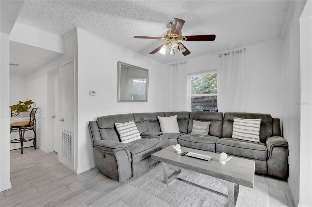 A living room features a gray sectional sofa, a coffee table, and a ceiling fan — 1101 28TH STREET NW, WINTER HAVEN, FL