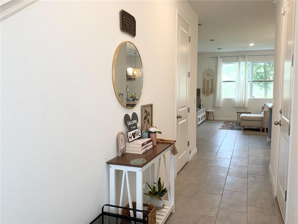 A hallway with a console table, mirror, and tile flooring leads into a living area — 864 LONGBOAT DRIVE, DAVENPORT, FL