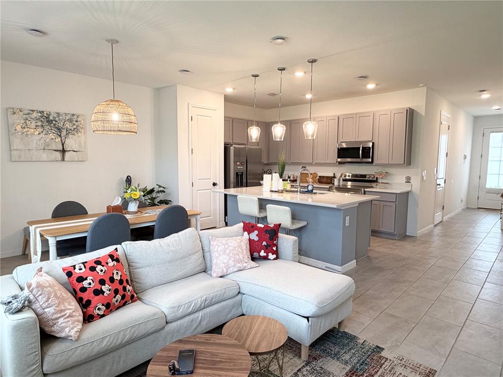 An open-concept kitchen and living area features gray cabinets, a kitchen island, and dining space — 864 LONGBOAT DRIVE, DAVENPORT, FL