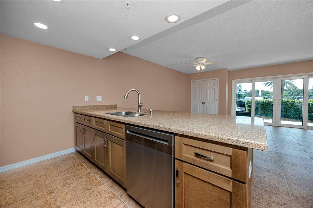 A kitchen island with a stainless steel dishwasher and sink sits on a tiled floor — 50 GULF BOULEVARD UNIT 108, INDIAN ROCKS BEACH, FL