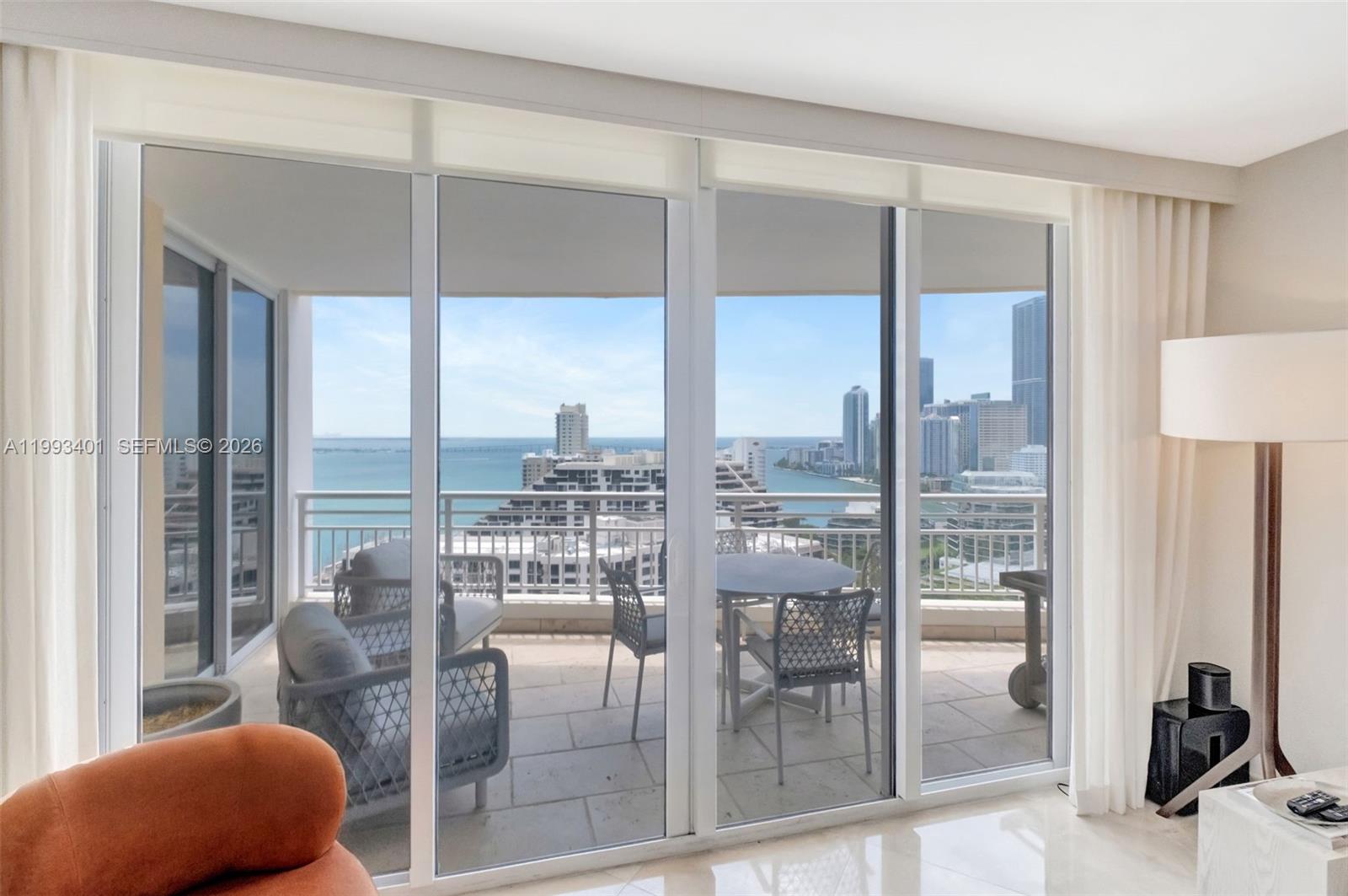 A living room features large sliding glass doors opening onto a balcony with city views — 848 Brickell Key Dr # 2605, Miami FL 33131, MIAMI, FL