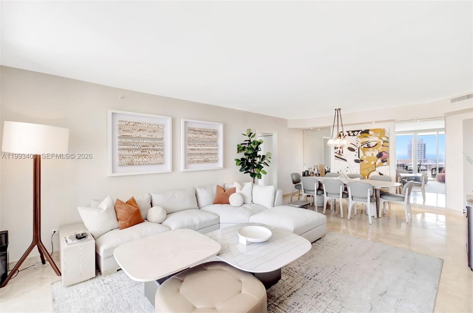 A bright living and dining area features a white sectional sofa, marble tables, and artwork — 848 Brickell Key Dr # 2605, Miami FL 33131, MIAMI, FL