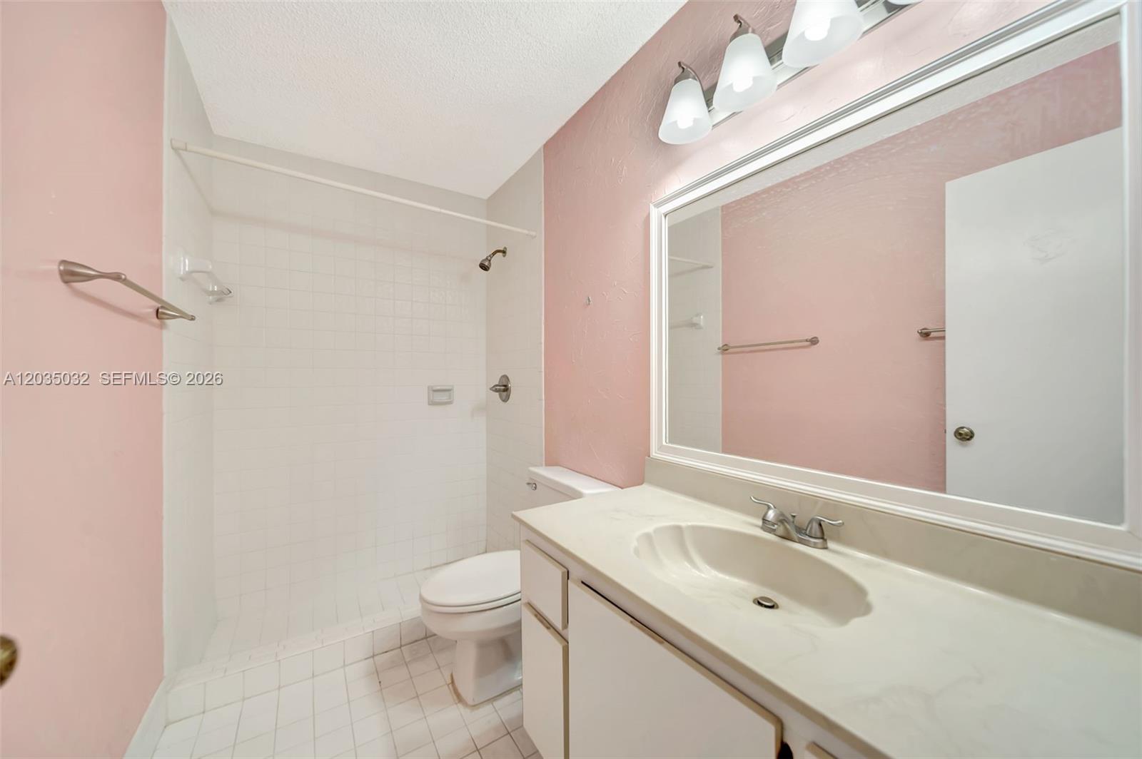 A bathroom features a white vanity, a large mirror, a toilet, and a tiled shower — 5223 W Gate Lake Rd # 5223, Tamarac FL 33319, TAMARAC, FL