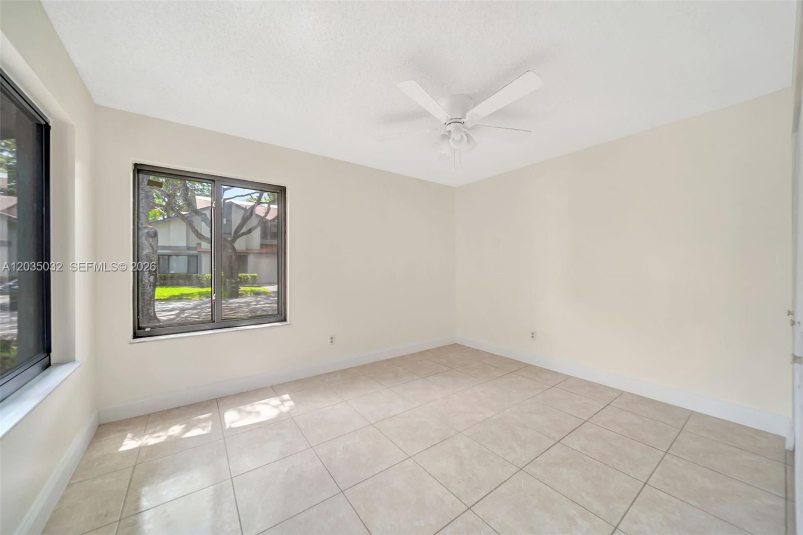 An empty bedroom features light-colored tile flooring, white walls, a ceiling fan, and a window — 5223 W Gate Lake Rd # 5223, Tamarac FL 33319, TAMARAC, FL