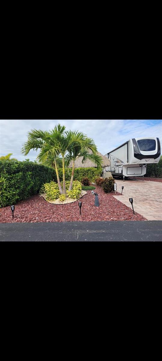 A palm tree stands in a red rock garden next to a parked recreational vehicle — 529 SW 39th Cove, Okeechobee FL 34974, OKEECHOBEE, FL