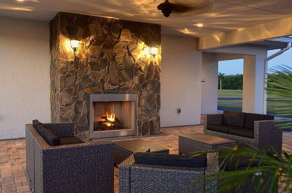 An outdoor patio features a stone fireplace, wicker furniture, and a paved floor — 529 SW 39th Cove, Okeechobee FL 34974, OKEECHOBEE, FL