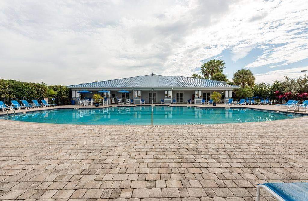 A swimming pool sits in front of a clubhouse with a blue metal roof — 529 SW 39th Cove, Okeechobee FL 34974, OKEECHOBEE, FL