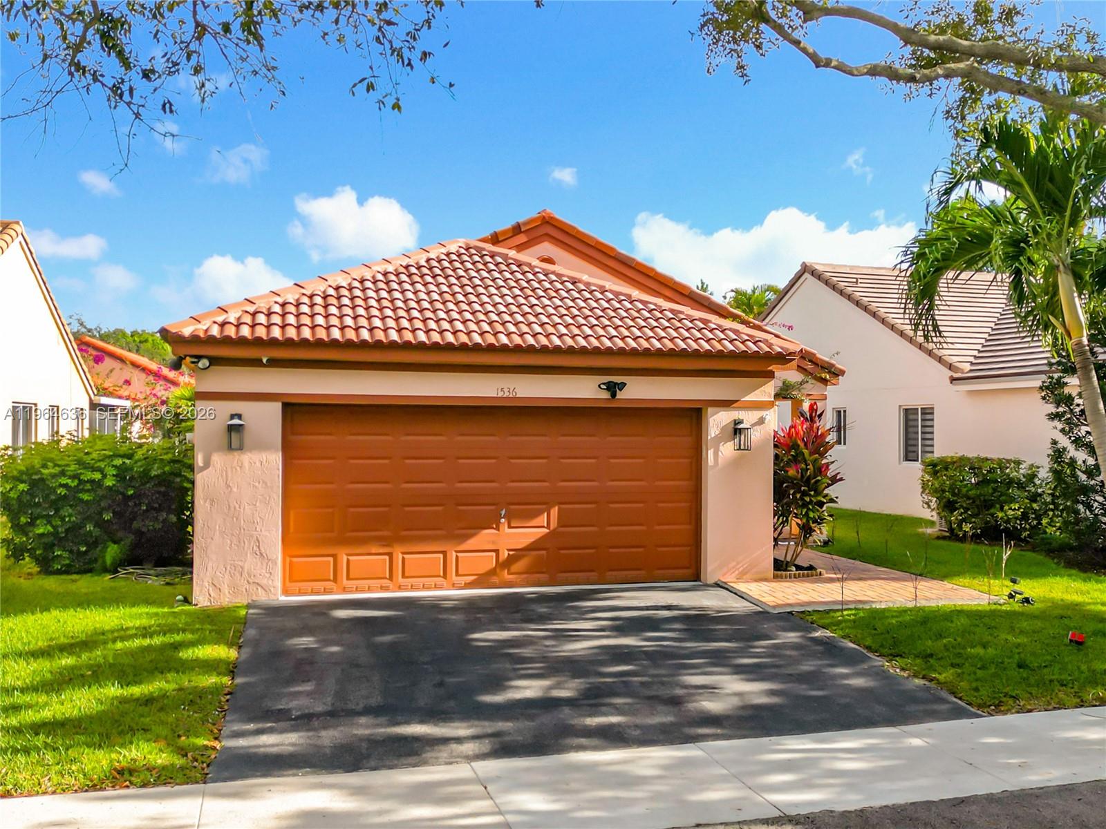 A single-story house with a terracotta tile roof and a two-car garage — 1536 Presidio Dr, Weston FL 33327, WESTON, FL