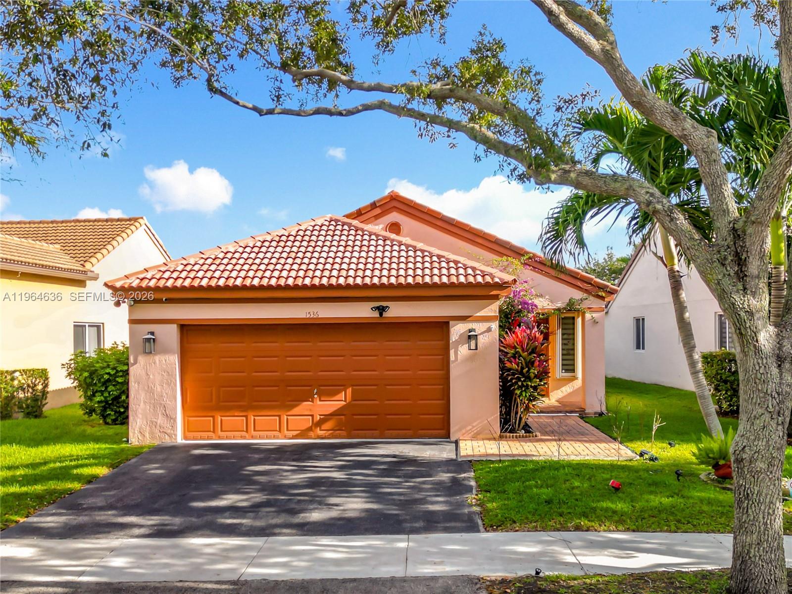 A single-story house with a terracotta tile roof, orange garage door, and a paved walkway — 1536 Presidio Dr, Weston FL 33327, WESTON, FL