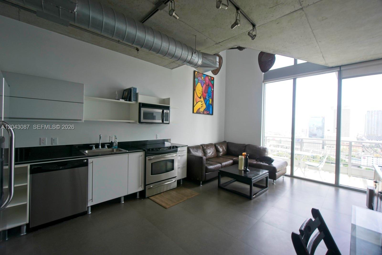 A modern studio apartment features a kitchen, living area, concrete ceiling, and floor-to-ceiling windows — 690 SW 1 Ct # 2703, Miami FL 33130, MIAMI, FL