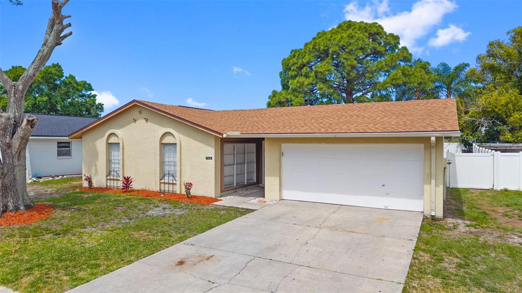 A single-story house with a tan stucco exterior, a two-car garage, and a brown roof — 7516 ARMAND CIRCLE, TAMPA, FL