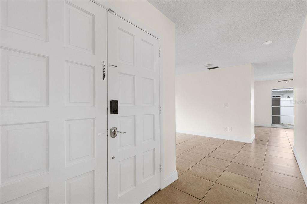 A white front door opens into a tiled entryway leading to an open living area — 7516 ARMAND CIRCLE, TAMPA, FL