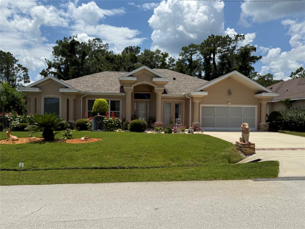 A tan, single-story house with a two-car garage and a landscaped front lawn — 96 ESPERANTO DRIVE, PALM COAST, FL