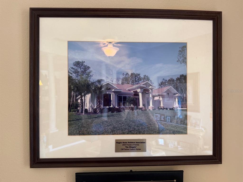 A framed photograph of a single-story house exterior displayed on a wall — 96 ESPERANTO DRIVE, PALM COAST, FL