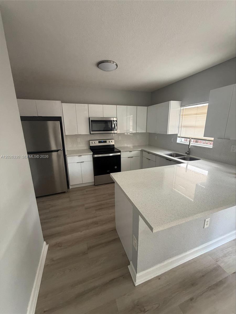 A modern kitchen features white cabinets, stainless steel appliances, and light-colored quartz countertops — 14773 SW 9th Ln # 0, Miami FL 33194, MIAMI, FL