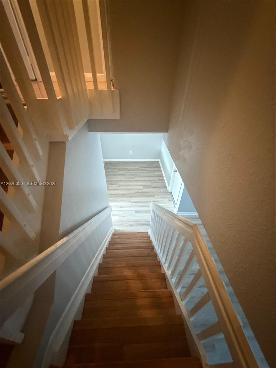 A wooden staircase with white railings leads down to a room with light-colored flooring — 14773 SW 9th Ln # 0, Miami FL 33194, MIAMI, FL
